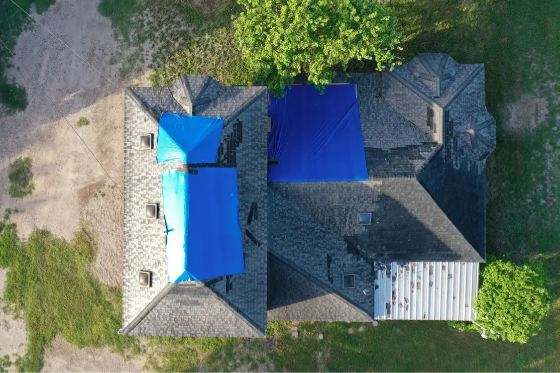 Techo dañado por tormenta cubierto con lonas azules en Mission