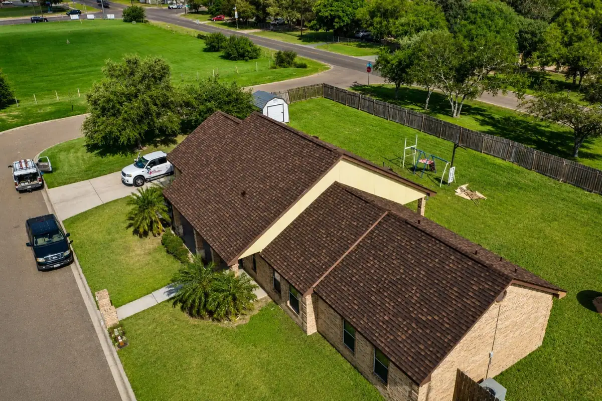 Vista de dron de un techo terminado de tejas de asfalto arquitectónicas color café en una casa de ladrillo del Valle del Río Grande
